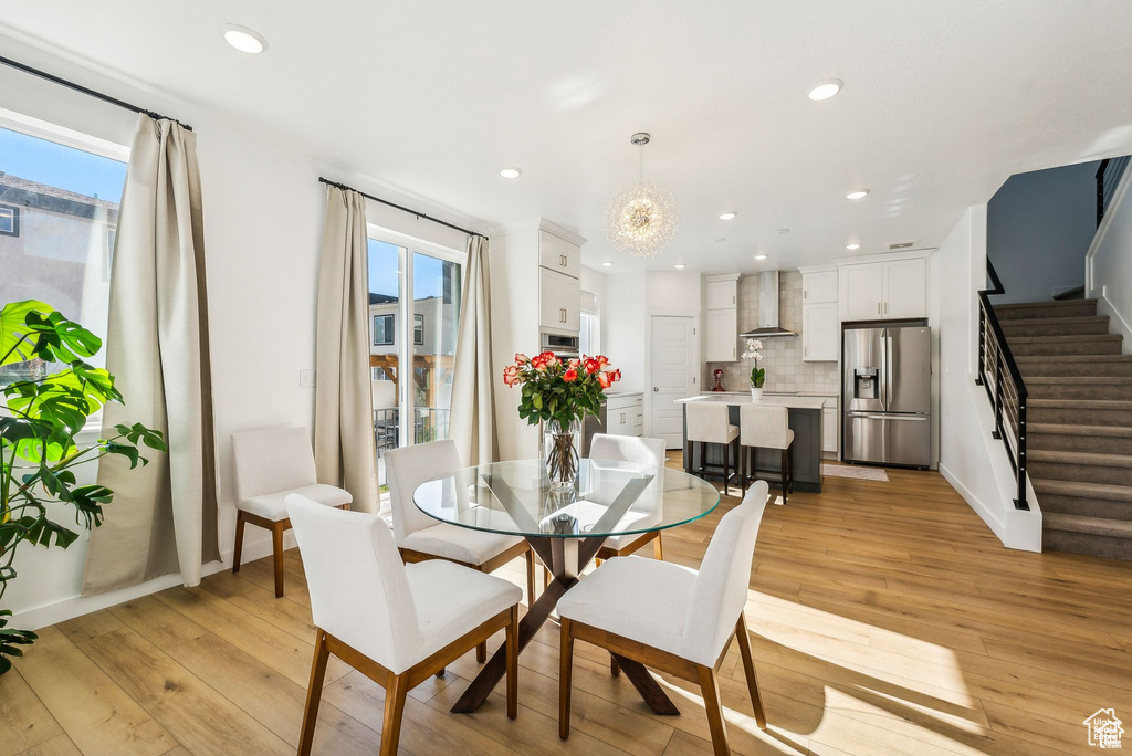 Dining area featuring stairs, light wood-style floors, recessed lighting, baseboards, and a chandelier