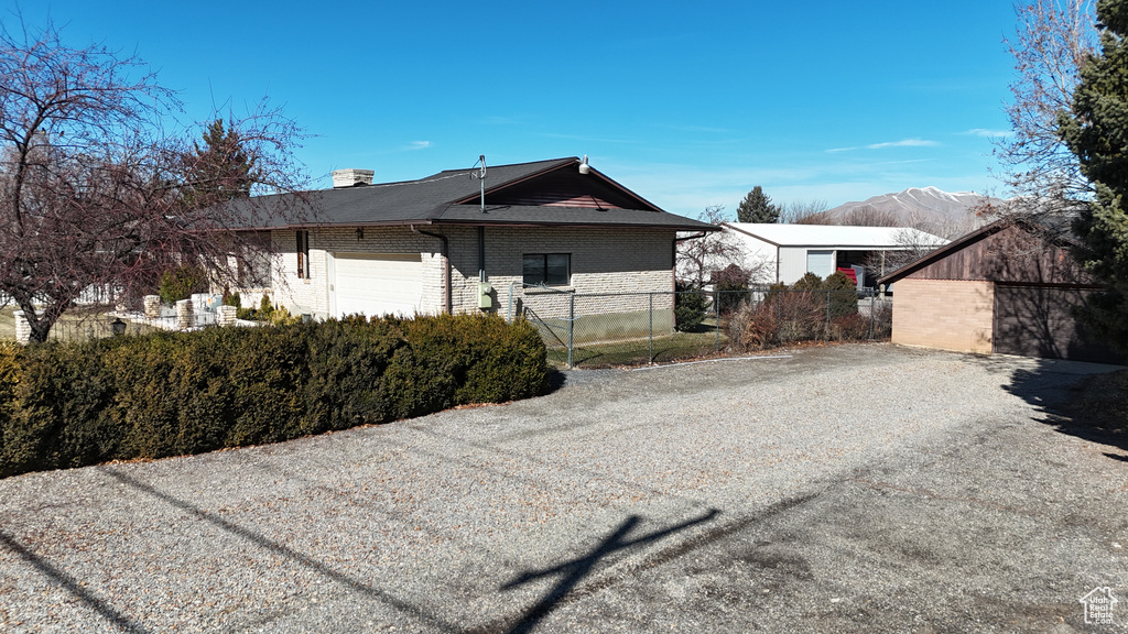 View of front of home featuring brick siding, fence, a garage, and a mountain view