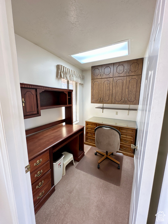 Carpeted office featuring plenty of natural light and built in desk