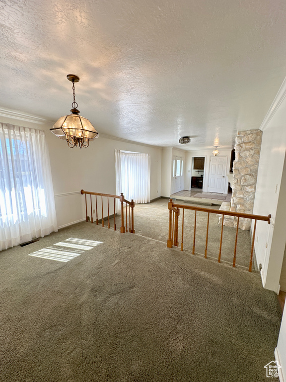 Carpeted spare room featuring a chandelier and a textured ceiling