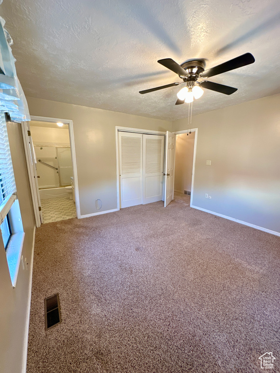 Unfurnished bedroom featuring baseboards, a textured ceiling, a closet, connected bathroom, and carpet floors