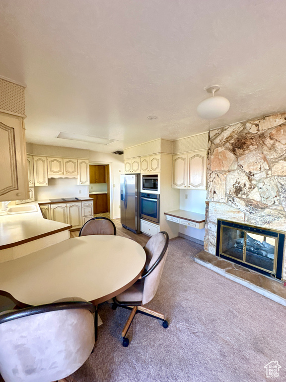 Dining space with a stone fireplace and carpet