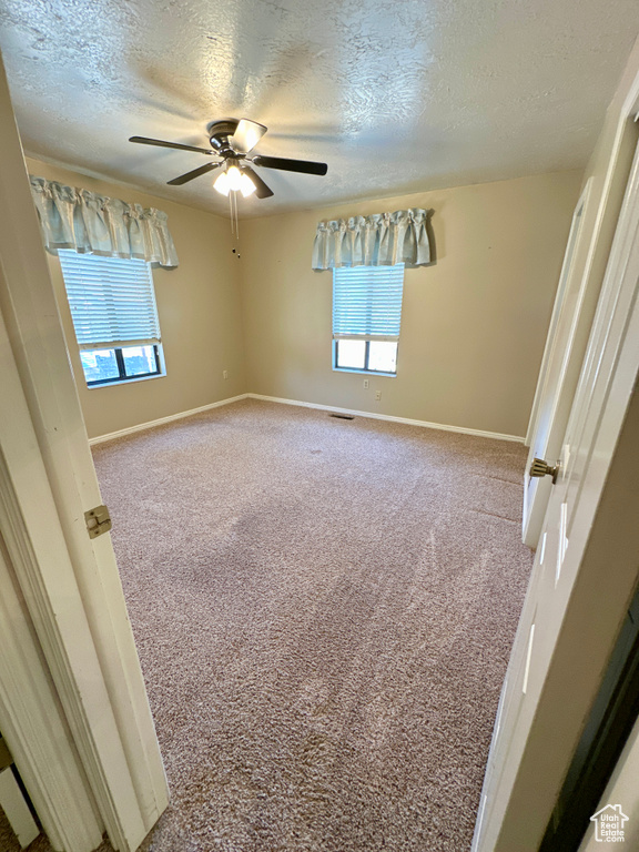 Unfurnished room featuring a textured ceiling, carpet, a ceiling fan, and baseboards