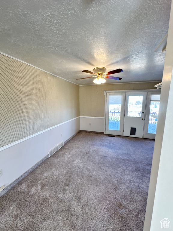 Empty room featuring a textured ceiling, a ceiling fan, and carpet floors