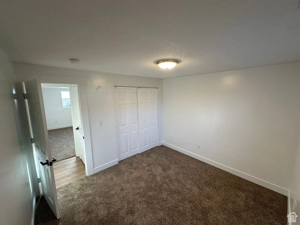 Unfurnished bedroom featuring carpet flooring, baseboards, and a closet