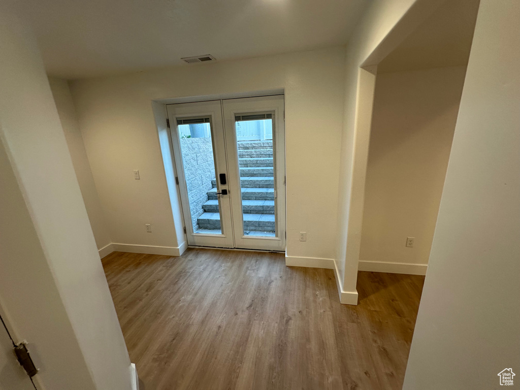 Doorway featuring french doors, baseboards, and wood finished floors