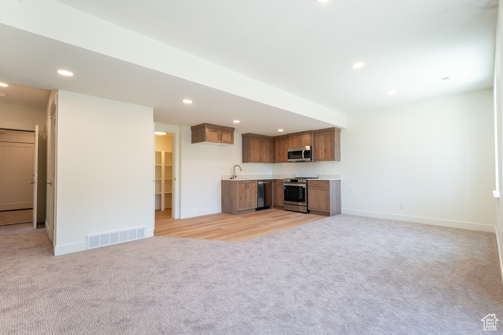 Unfurnished living room featuring light colored carpet, wet bar, and recessed lighting