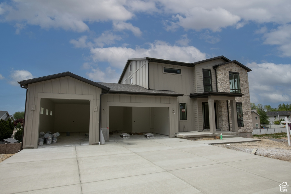 View of front facade featuring driveway, an attached garage, and stone siding