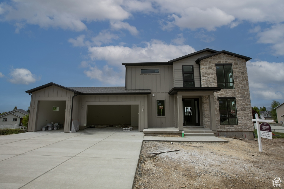 View of front of property with concrete driveway, board and batten siding, a garage, and stone siding