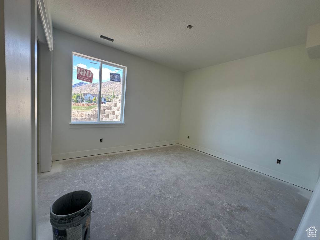 Spare room with a textured ceiling and baseboards