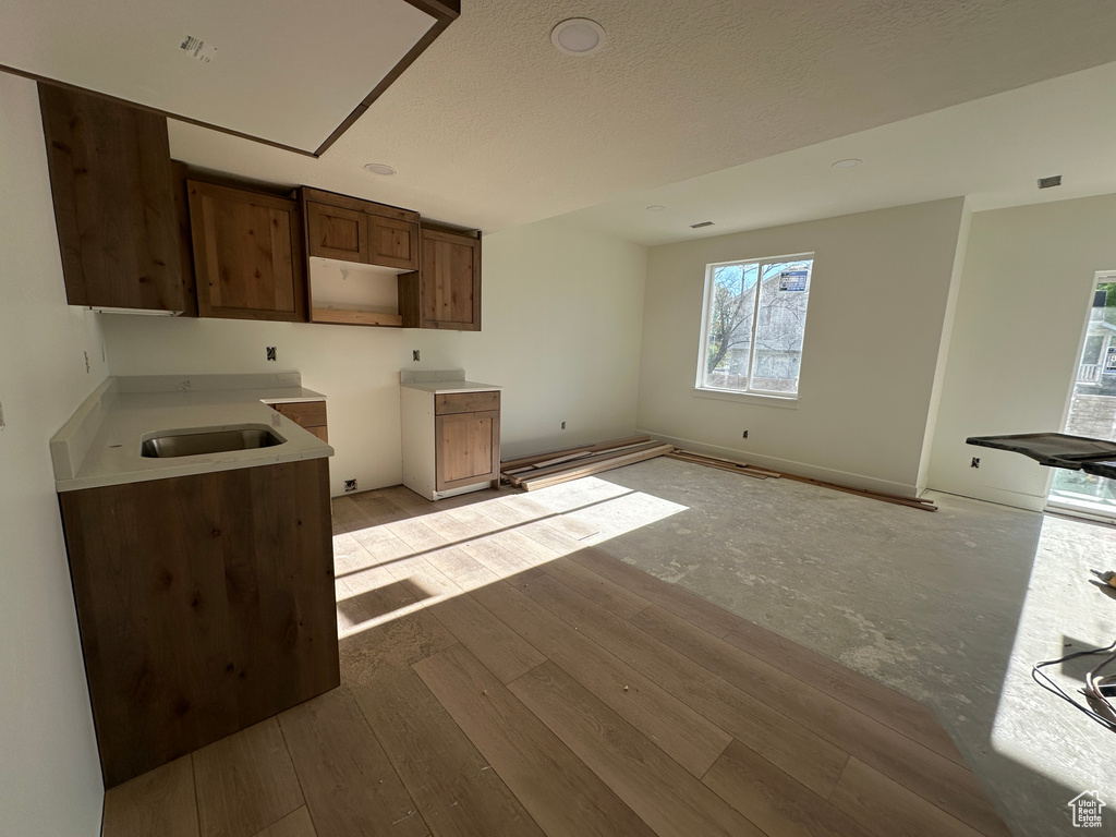 Kitchen featuring a sink, light wood-type flooring, and a textured ceiling