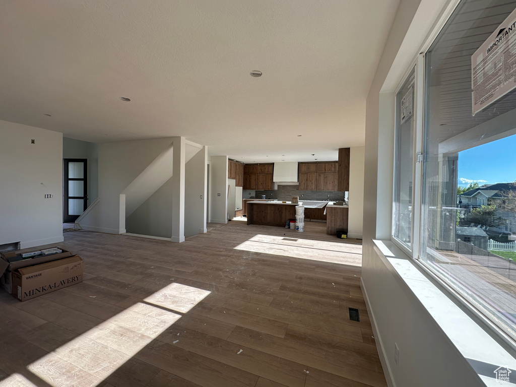 Unfurnished living room featuring dark wood-style flooring and baseboards