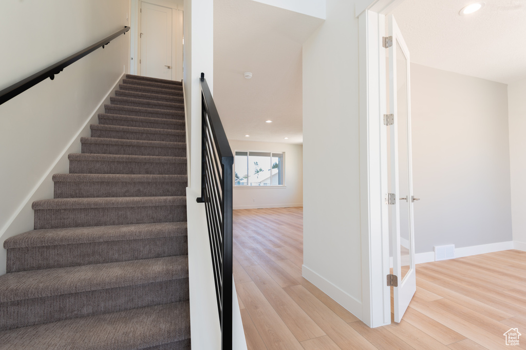 Stairs with wood finished floors and recessed lighting