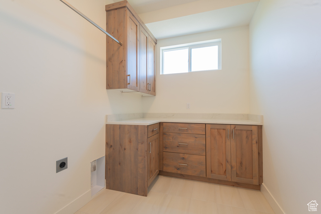 Washroom featuring electric dryer hookup and cabinet space
