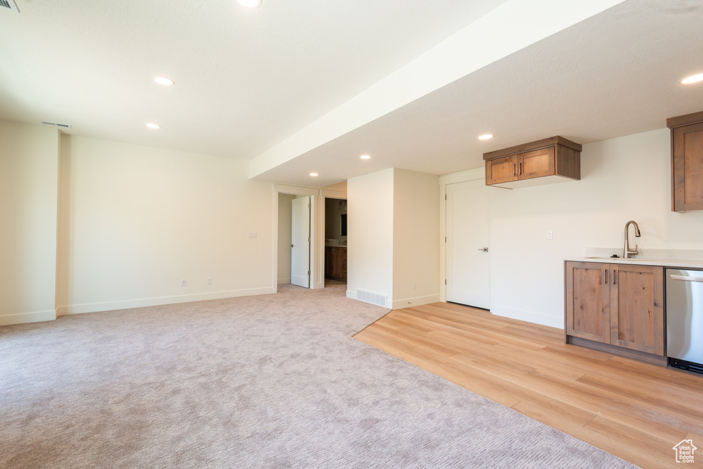 Kitchen with dishwasher, recessed lighting, light countertops, light colored carpet, and brown cabinetry