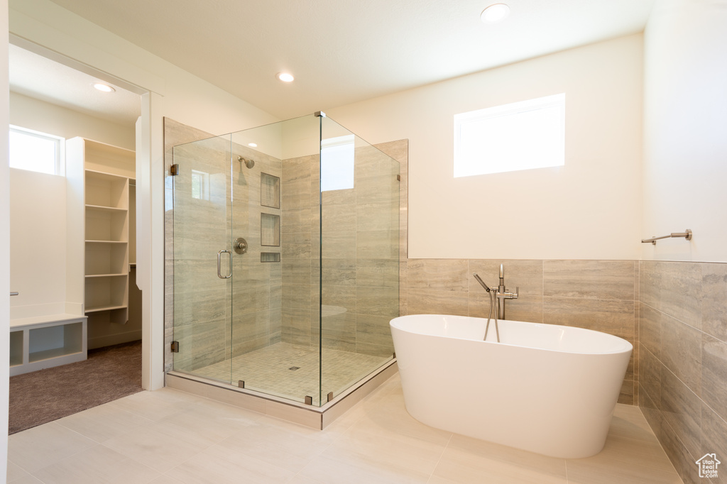 Full bathroom with a shower stall, a freestanding bath, tile walls, recessed lighting, and a wainscoted wall