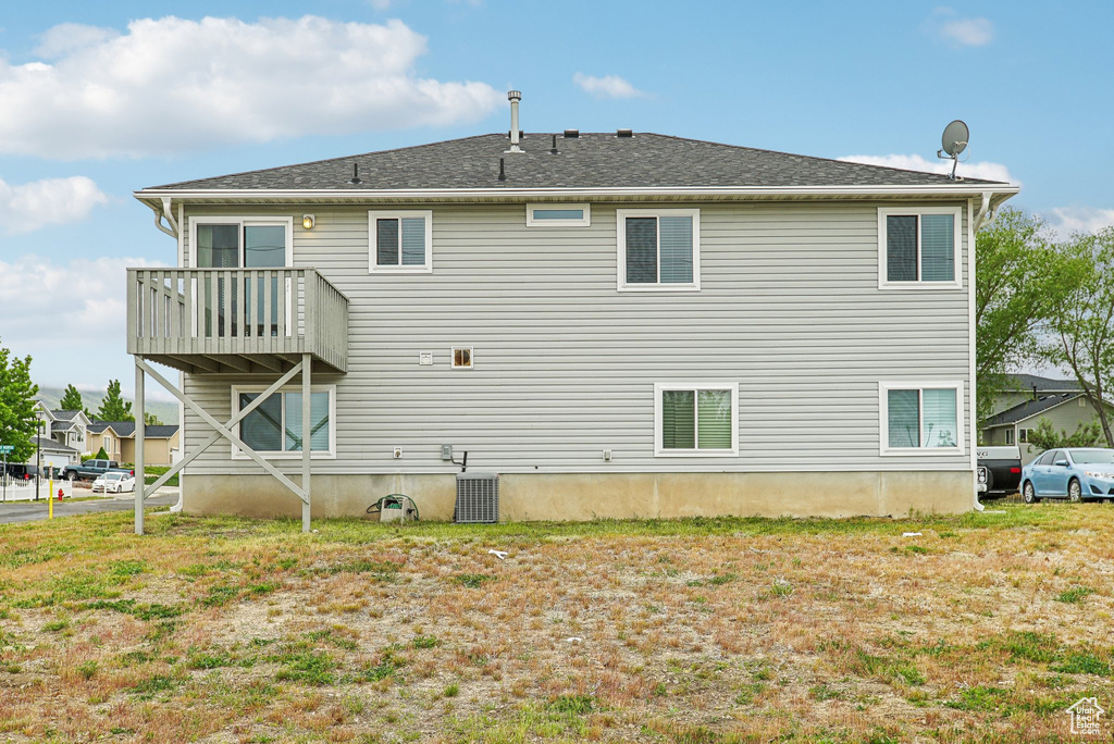 Back of property with central air condition unit and a balcony
