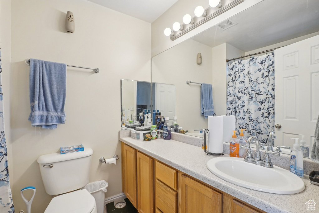 Bathroom with toilet, vanity, and a shower with curtain