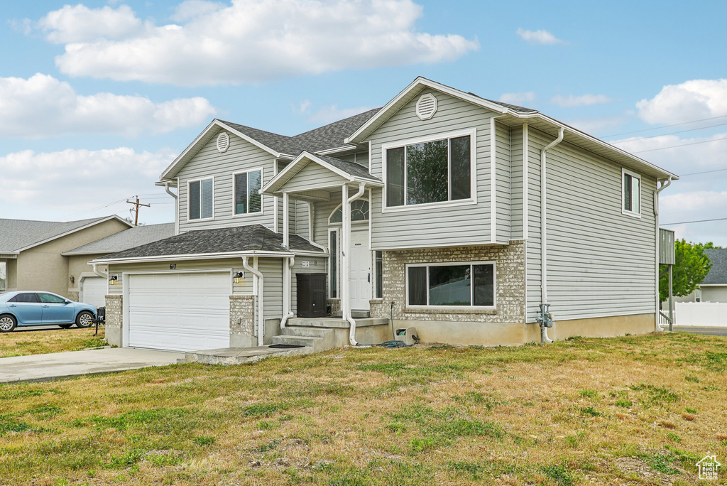 View of front of home featuring concrete driveway, a front lawn, and an attached garage