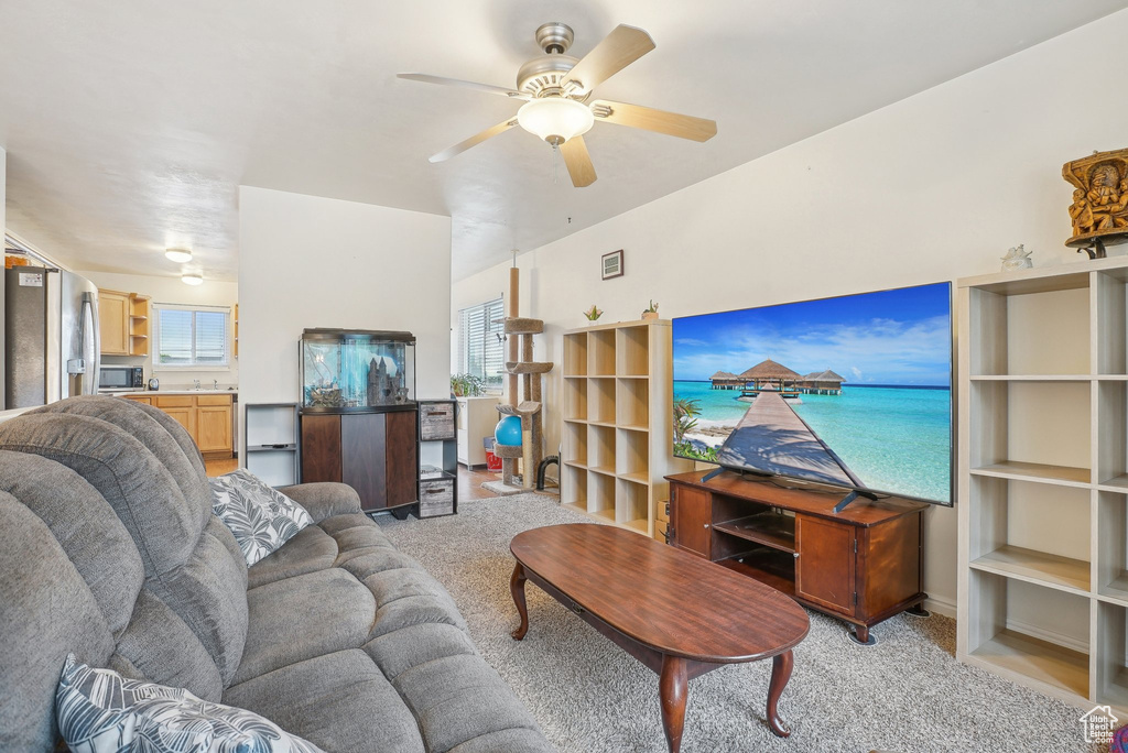 Living room with healthy amount of natural light, a ceiling fan, and light carpet