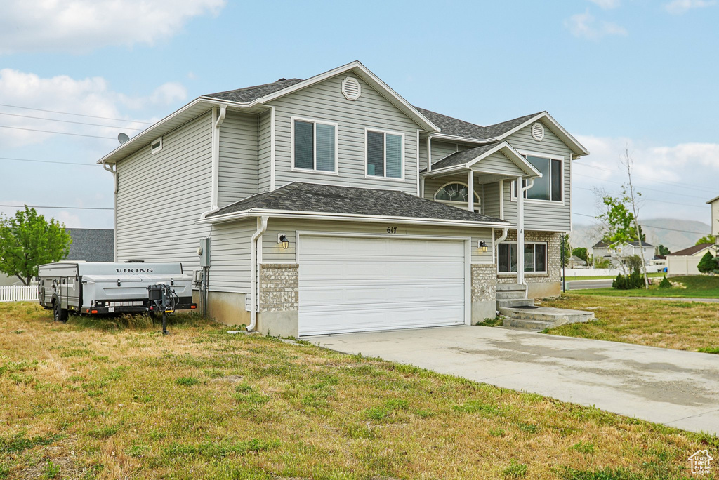 View of front of house featuring an attached garage, driveway, a front yard, and a shingled roof