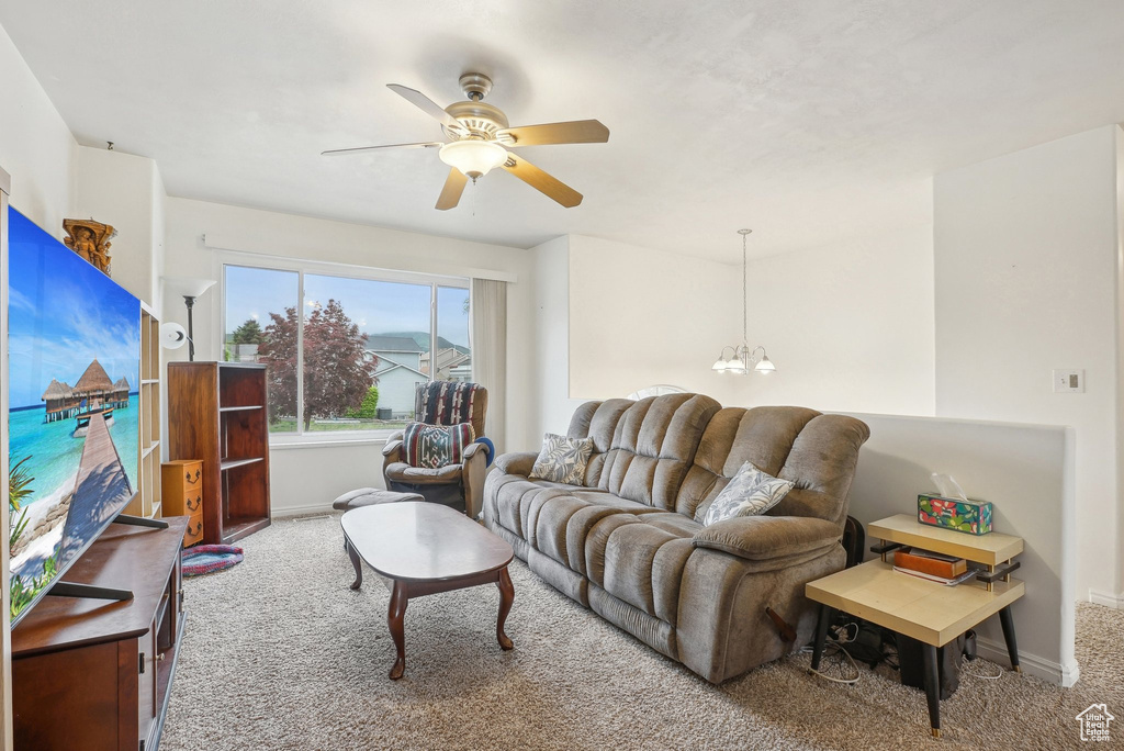 Carpeted living room featuring a ceiling fan, baseboards, and a chandelier