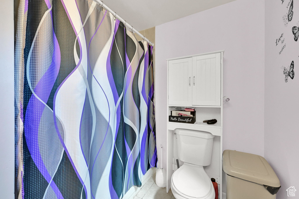 Bathroom featuring toilet, tile patterned floors, and curtained shower