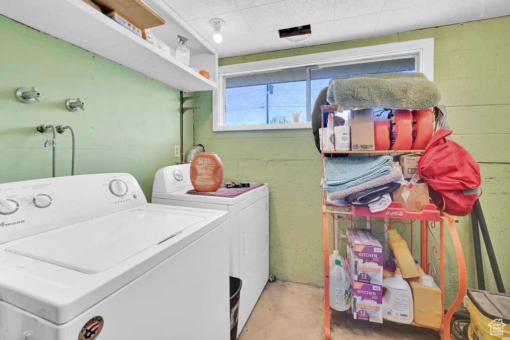 Washroom with washer and clothes dryer and concrete block wall