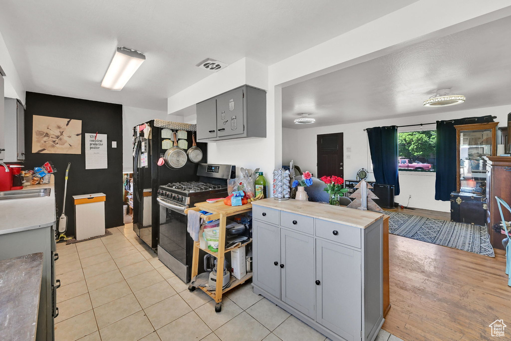Kitchen featuring gas range, gray cabinets, a peninsula, and light countertops