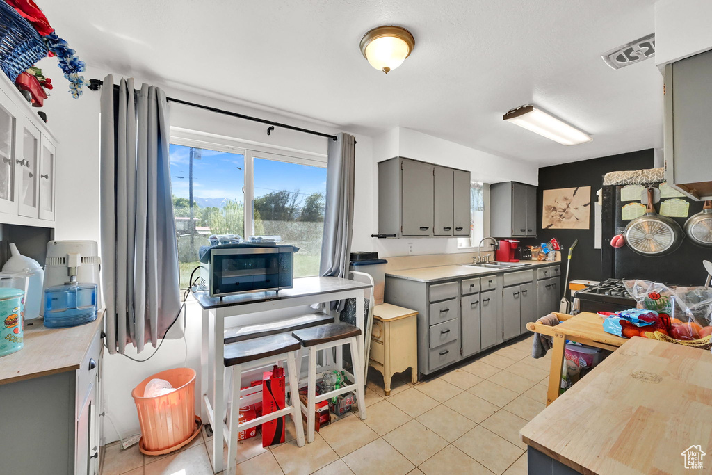 Kitchen featuring gray cabinetry, a sink, light tile patterned floors, and light countertops