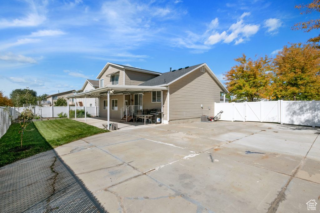 Back of house with a patio, driveway, and a gate