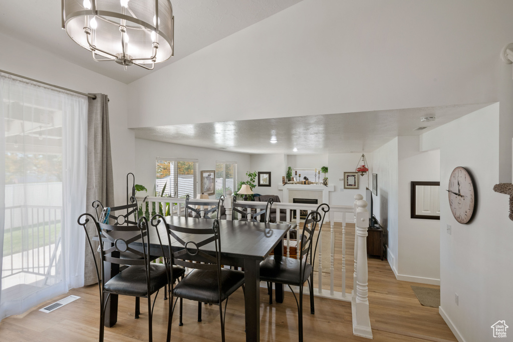 Dining area with light wood-style flooring, a chandelier, baseboards, and a fireplace