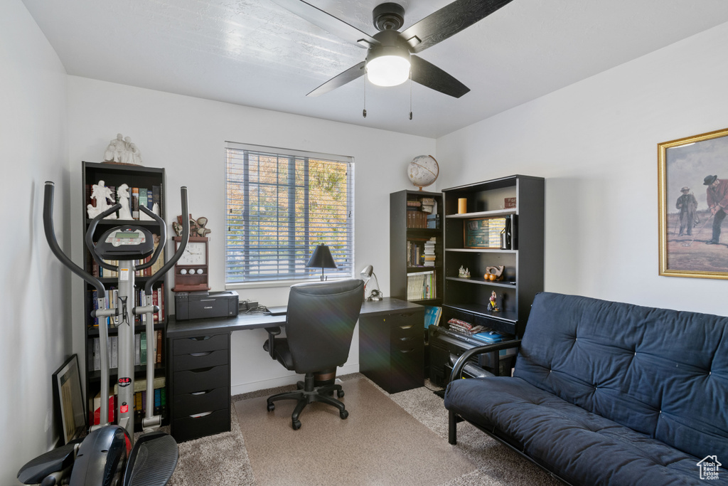 Carpeted office space featuring ceiling fan and baseboards