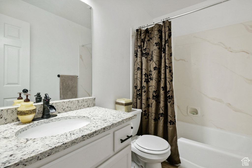 Bathroom featuring toilet, vanity, and shower / bath combo with shower curtain