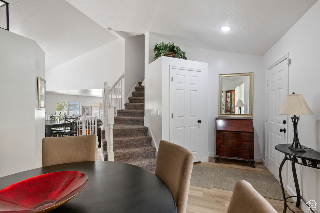 Dining space featuring wood finished floors, stairs, vaulted ceiling, recessed lighting, and baseboards