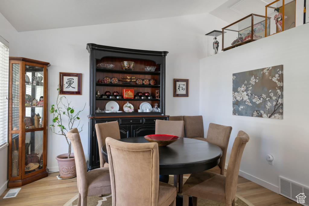 Dining room featuring lofted ceiling, light wood-type flooring, and baseboards
