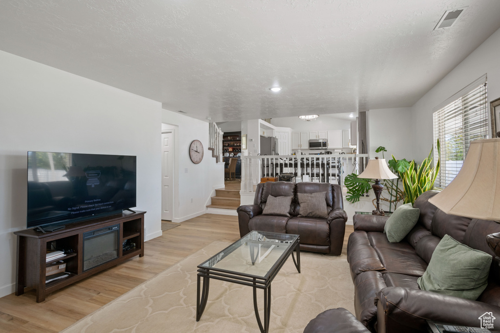Living area featuring light wood-type flooring, stairs, and baseboards