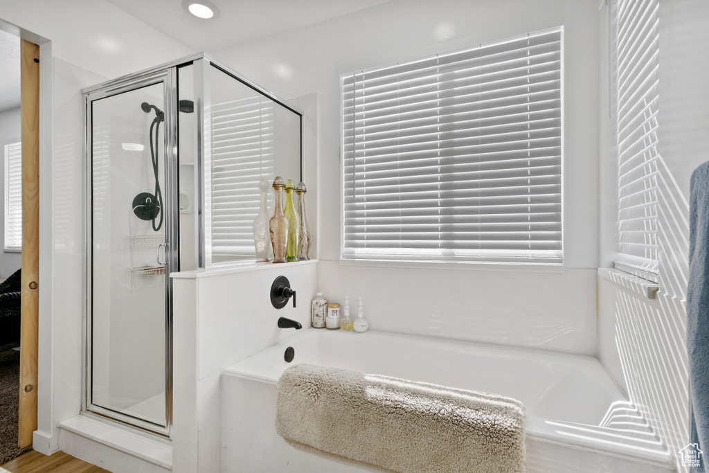 Full bath with a shower stall, a bath, and wood finished floors