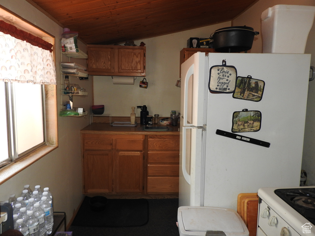 Kitchen with white appliances, wood ceiling, and brown cabinetry