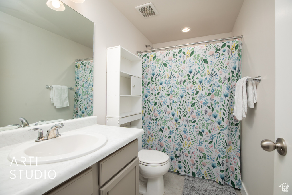 Bathroom featuring tile patterned floors, vanity, toilet, and curtained shower
