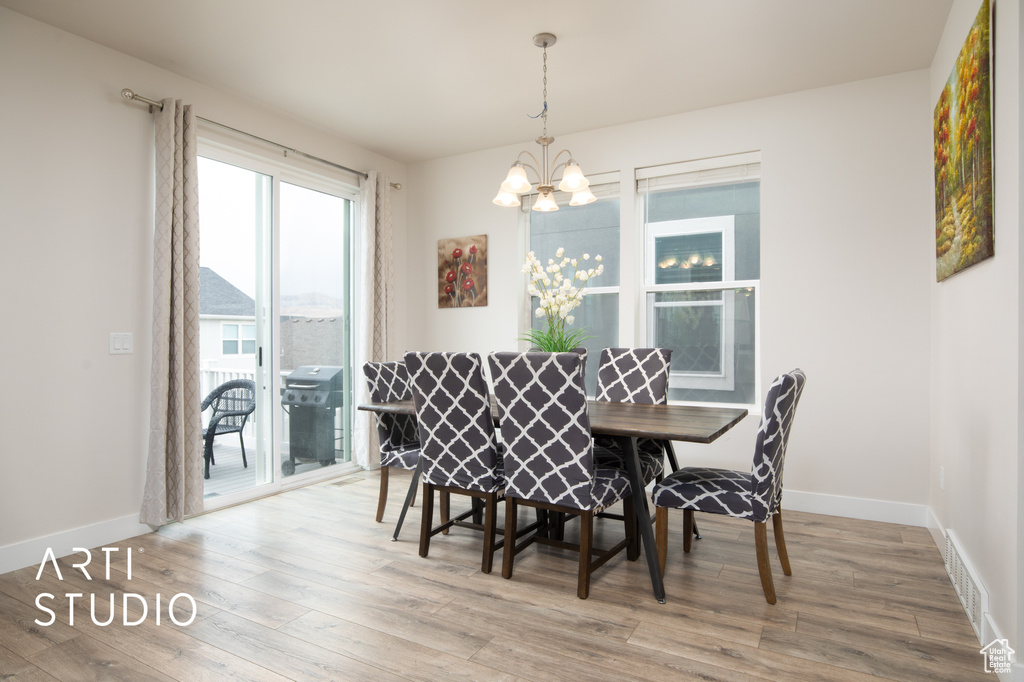 Dining area with a chandelier, wood finished floors, and baseboards