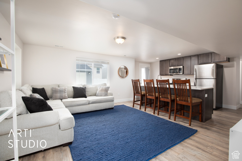 Living area with light wood finished floors, baseboards, and recessed lighting