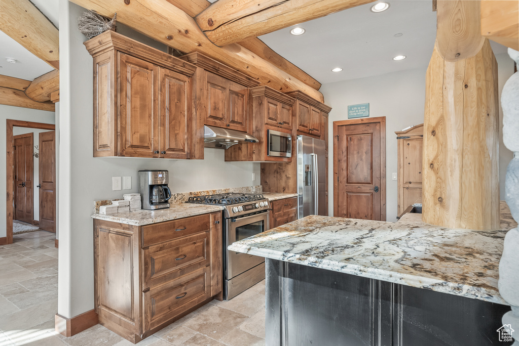 Kitchen with stainless steel appliances, stone tile flooring, recessed lighting, under cabinet range hood, and light stone countertops