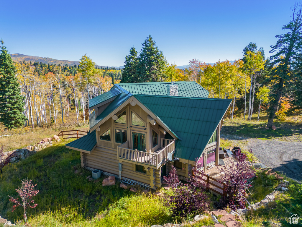 View of front of property featuring a forest view, log exterior, metal roof, and a standing seam roof