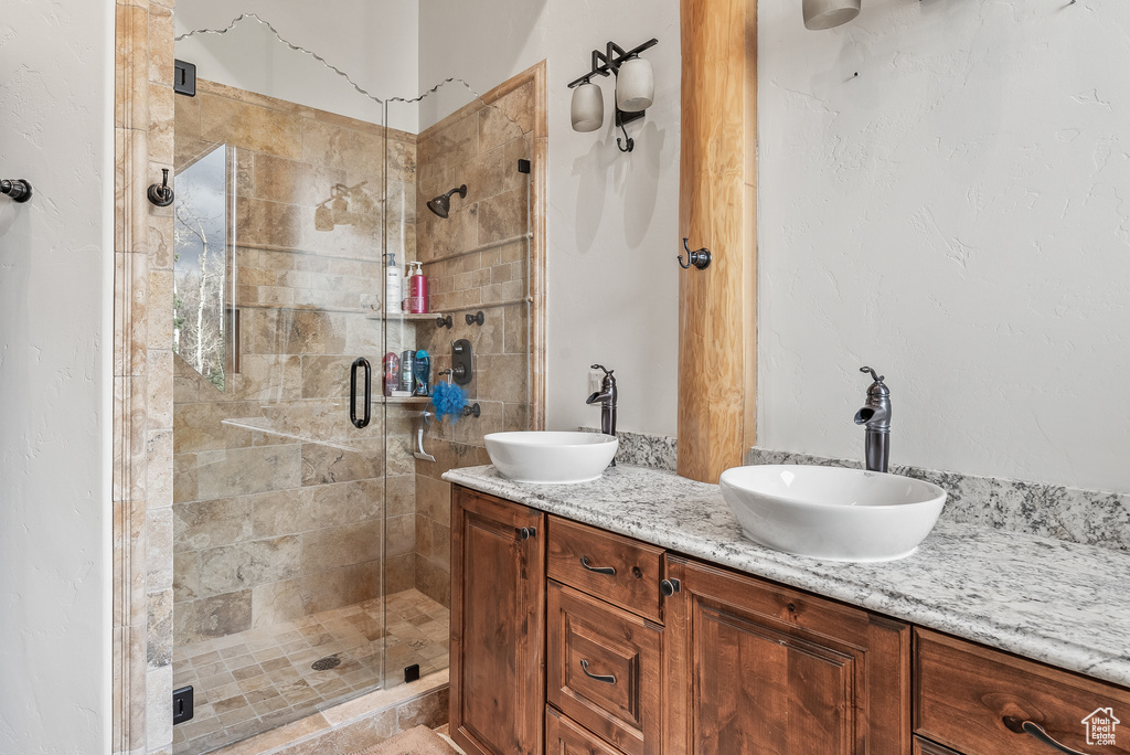 Bathroom with a sink, double vanity, and a stall shower