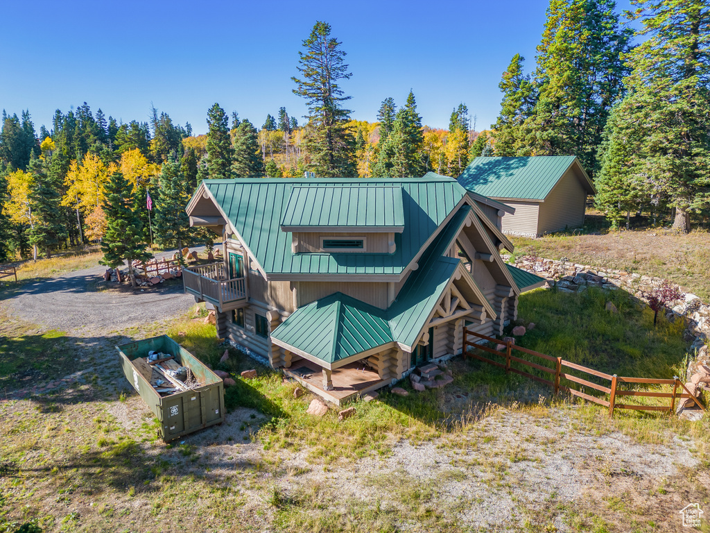 Back of property with metal roof, a standing seam roof, fence, and log exterior