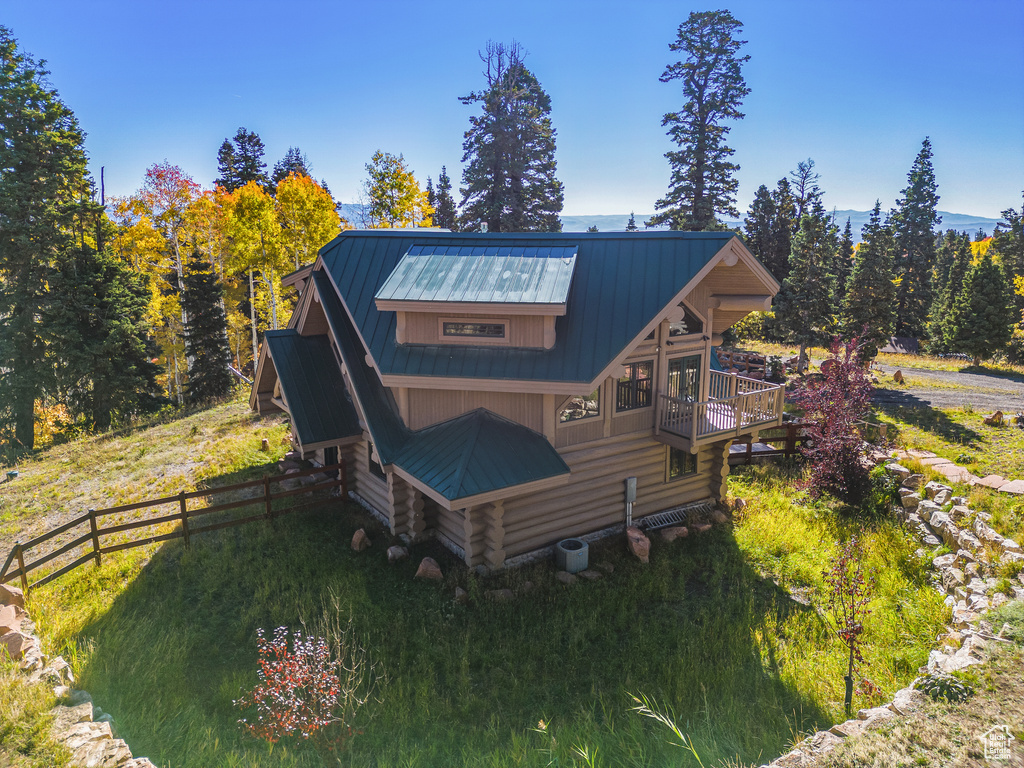 Back of house with fence, log exterior, and metal roof