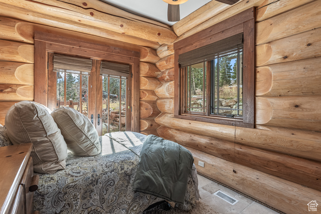 Bedroom with visible vents, access to exterior, multiple windows, and log walls