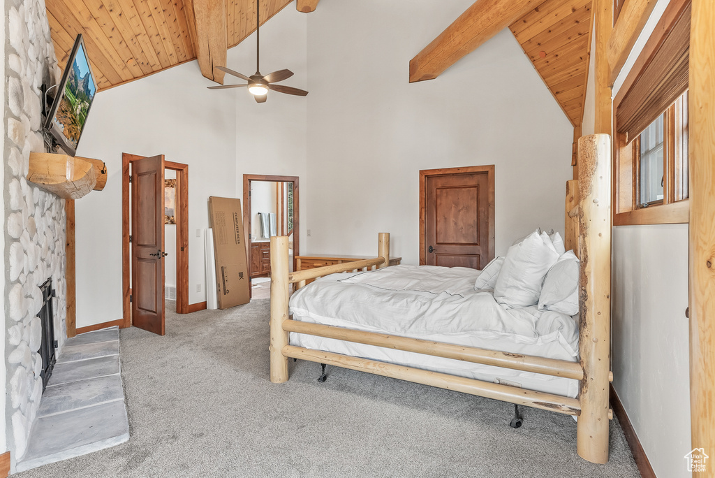 Bedroom featuring carpet flooring, wood ceiling, high vaulted ceiling, beamed ceiling, and a fireplace