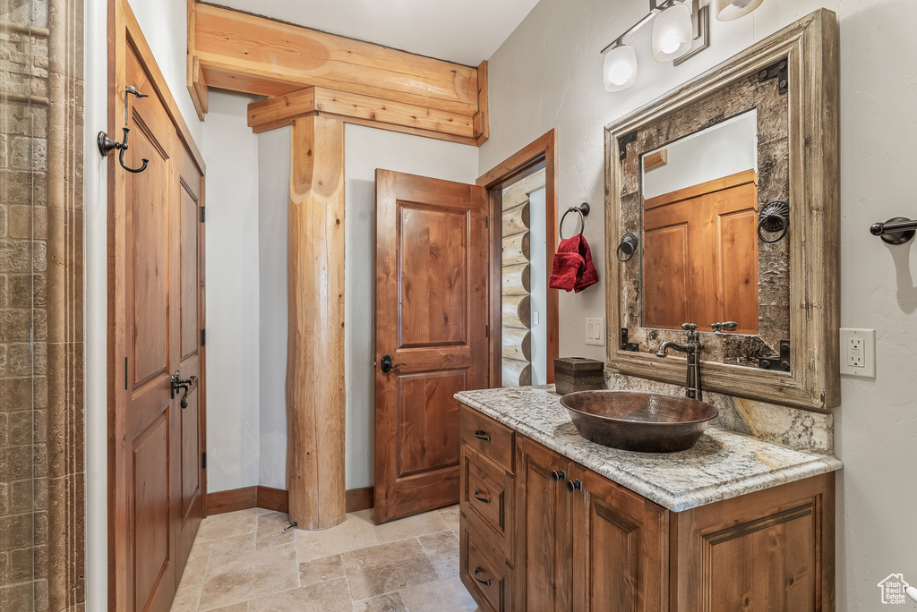 Bathroom featuring vanity, baseboards, and stone finish flooring